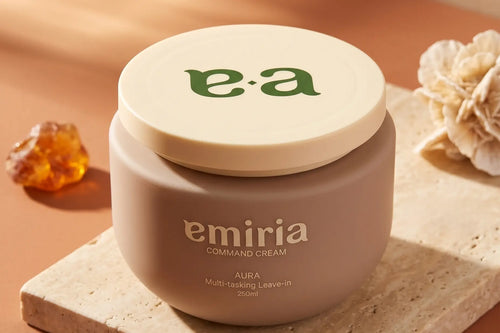 Jar of emiria cream with a decorative stone and flower on a warm-toned background