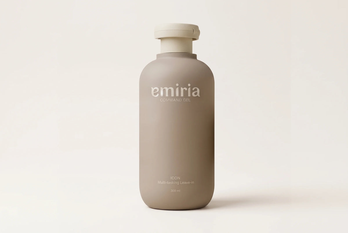 A matte taupe-beige bottle of emiria Ion Moisturizing Lotion with a matching cap, centered on a warm off-white background.
